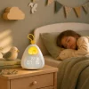 reveil-enfant-oisillon-chambre-enfant-ambiance-douce Réveil enfant oisillon posé sur une table de nuit dans une chambre d’enfant avec ambiance douce et veilleuse rassurante